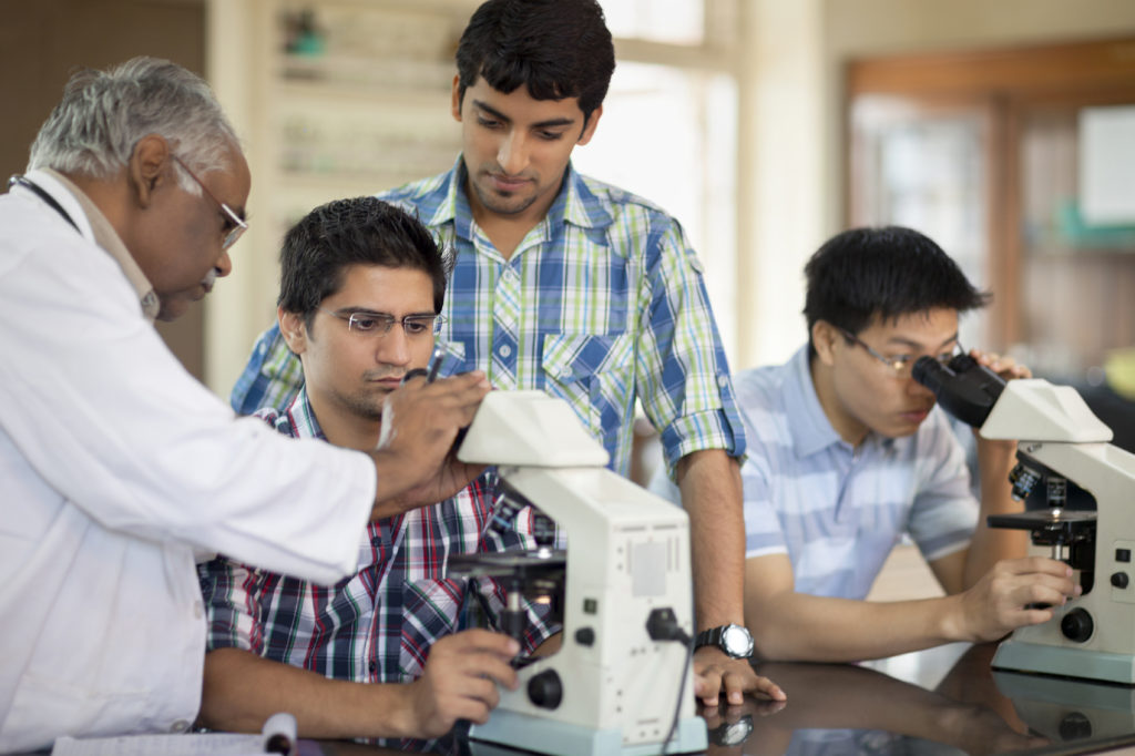 Portrait Of Students Looking Through Microscope