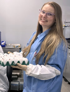 Nina Byloff in the laboratory, holding a tray of eggs used in viral production processes.